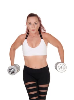 A middle age woman standing from the front lifting her two dumbbells.whit her long red hair and workout outfit, isolated for white background.
