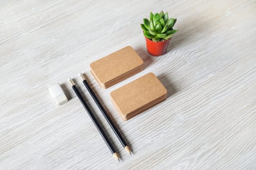 Blank branding mockup. Blank kraft business cards, pencils, eraser and plant on wooden background.