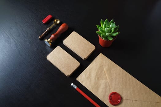 Kraft branding stationery set on black wood table background. Blank corporate ID template.