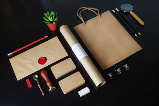Blank kraft stationery for branding design. Corporate identity set on black wooden background.