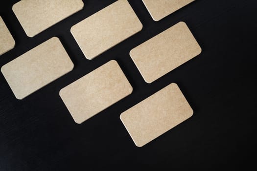 Mockup of kraft business cards on black wood table background. Flat lay.