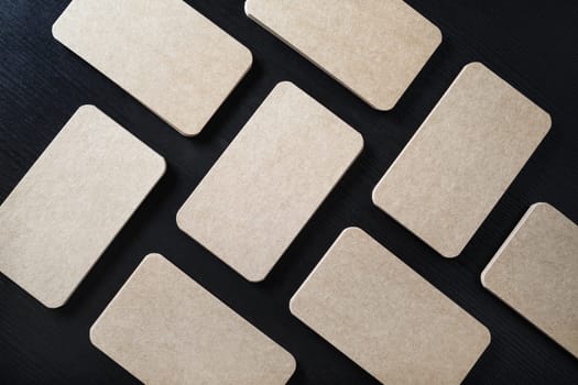 Kraft business cards mockup on black wood table background. Flat lay.