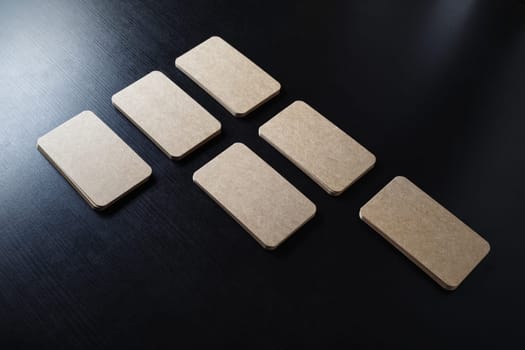 Photo of blank kraft business cards on black wooden background. Template for branding identity.
