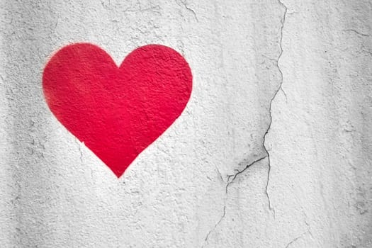 Red love heart hand drawn on grungy wall. Textured background trendy street style. Copy space.