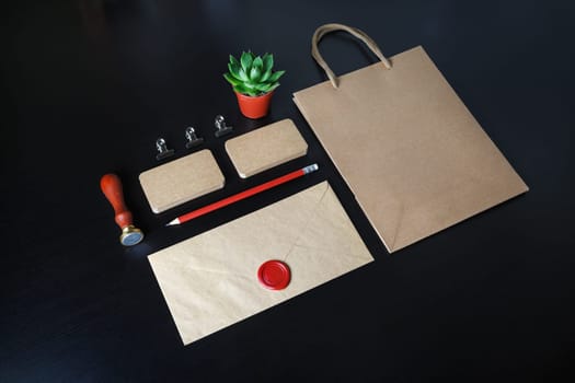 Blank kraft business stationery set. Corporate identity template on black wood table background.