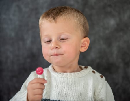 a cute child is eating a lollipop