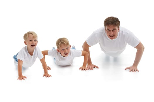 Father  with two sons. Young man with children isolated on a white background are doing gymnastic exercises. Push-ups. Parenting, Concept of healthy lifestyle, people and family