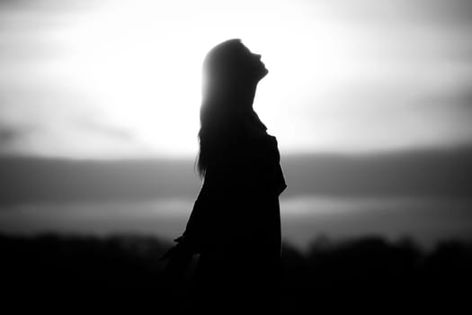 Silhouette in front of sunset or sunrise in summer nature. Symbol for healing burnout therapy, wellness relaxation or resurrection.