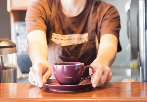 Barista offering purple cup of coffee, stock photo
