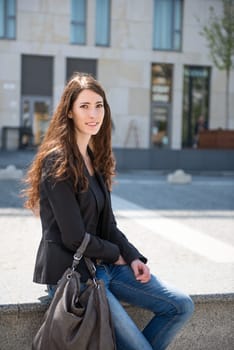 Young smiling happy woman in casual clothes - sitting, city surrounding