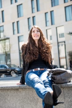Young smiling happy woman in casual clothes - sitting, city surrounding