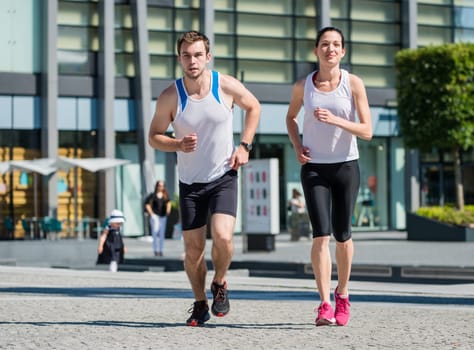 Young sport couple jogging together in city environment