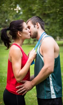 Young happy fitness couple kissing  - woman put skipping rope around men's neck