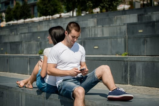 Young couple in street - man with smartphone, woman with tablet