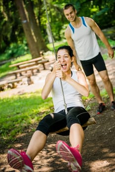 swinging on seesaw - young sport couple having fun