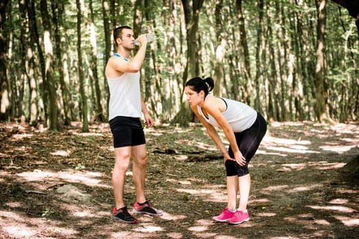 Sporting together - young couple relaxing after jogging in nature