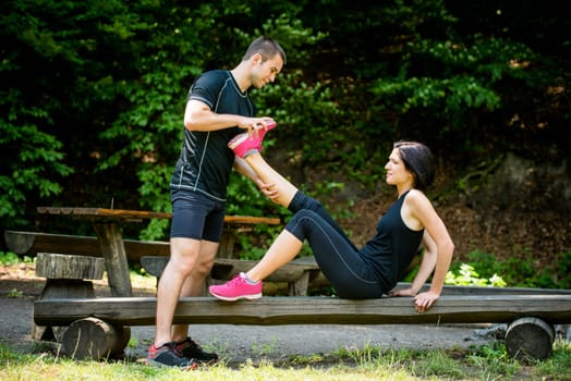 Man stretches womans leg - muscle spasm after sport training