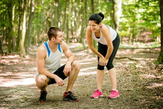 Sport couple relaxing after jogging in nature (foot bridge in forest)
