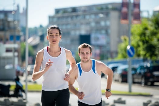 Young sport couple running together in city environment