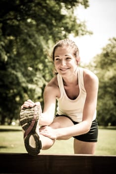 Young fitness woman stretching muscles before sport activity - outdoor in park