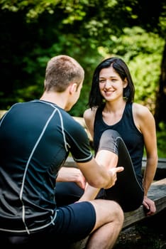 Young man gives massage of calf to his friend after sport training