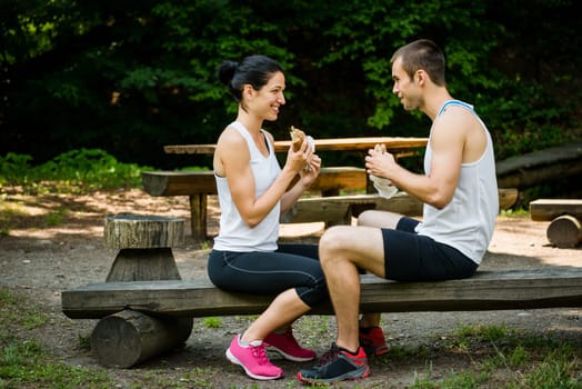 Young couple eating together after jogging outdoor in nature
