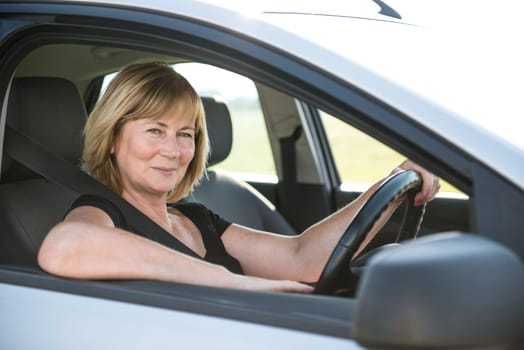 Portrait of attractive senior smiling woman sitting in car