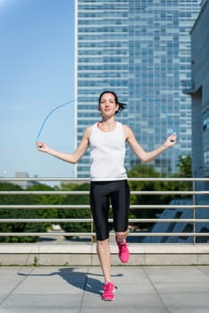 Young sport woman exercising with skipping rope in urban environment