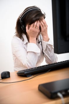 Young depressed business person (call center employee) with headache at computer
