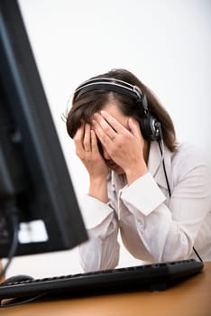 Young depressed business person (call center employee) with headache at computer