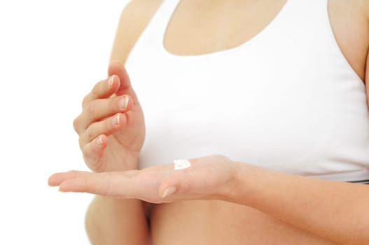 Woman in white applies cream on dry hands (focus on cream and fingers)