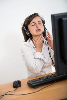 Young ill business woman with throat pain working with computer and headset