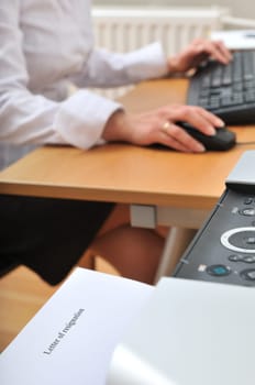 Detail of business woman on workplace. In front letter of resignation went from printer (shallow deptht of field).