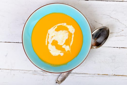 plate of pumpkin soup with spoon on a wooden table