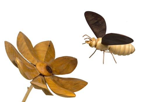 Model of a wooden bee flies towards a wooden flower, isolated on white