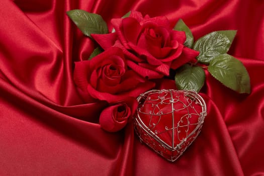 Abstract background from red silk (satin), roses and heart. Fabric texture with draped. Top view. Element design. Valentine's day. Wedding day.  Women' s day. Greeting card