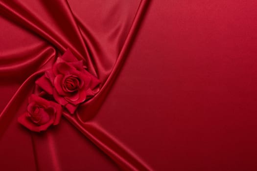 Abstract background from red silk (satin) and roses. Fabric texture with draped. Top view with copy space. Element design. Valentine's day. Wedding day. Women' s day. Greeting card