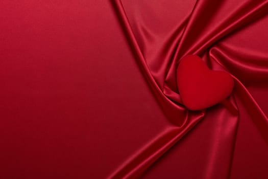 Abstract background from red silk (satin) and heart. Fabric texture with draped. Top view with copy space. Element design. Valentine's day. Wedding day. Greeting card