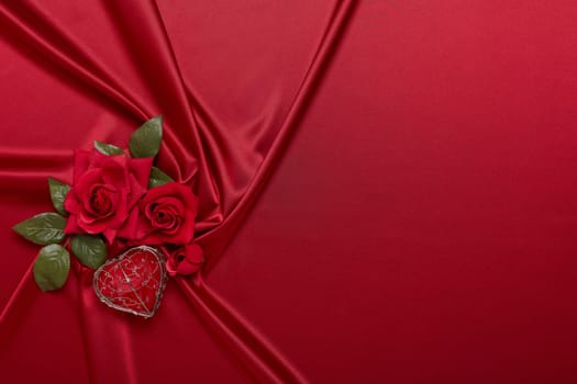 Abstract background from red silk (satin), roses and heart. Fabric texture with draped. Top view with copy space. Element design. Valentine's day. Wedding day.  Women' s day. Greeting card