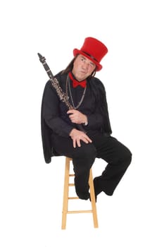 A middle age indigenous man holding his clarinet in a black outfit and.red hat and bow tie looking away, isolated for white background.