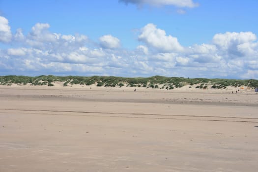 Sandy beach with sand dunes and blue sky in the background