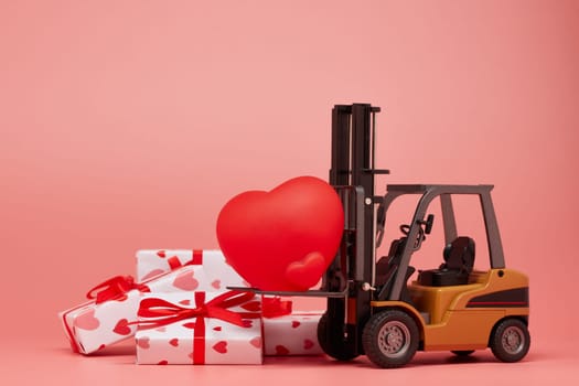 Forklift, red heart and gift boxes on pink background. Valentine's Day. Wedding Day