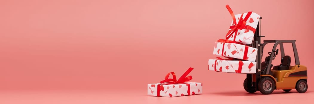 Forklift and gift boxes on pink background with copy space. Valentine's Day. Wedding Day