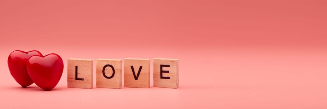 Two decorative hearts and inscription love from wooden letters on pink background with copy space. Valentine's Day. Wedding Day. Design element for romantic greeting card,  invitation.