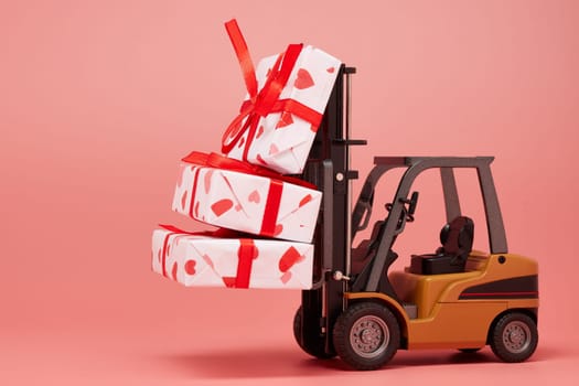 Forklift and gift boxes on pink background with copy space. Valentine's Day. Wedding Day