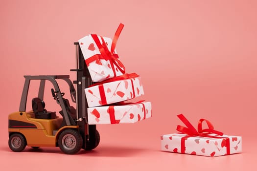 Forklift and gift boxes on pink background with copy space. Valentine's Day. Wedding Day