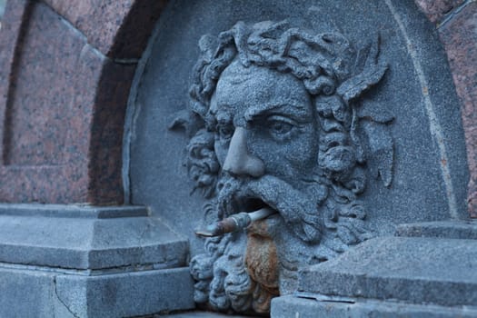 medieval street drinking fountain with stone human head