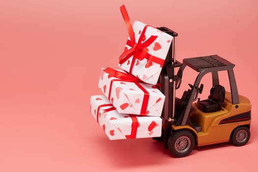 Forklift and gift boxes on pink background with copy space. Valentine's Day. Wedding Day