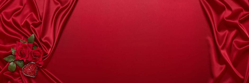 Abstract background from red silk (satin), roses and heart. Fabric texture with draped. Top view with copy space. Element design. Valentine's day. Wedding day.  Women' s day. Greeting card