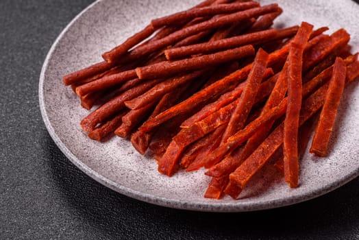 Jerky dried fish sticks with salt and spices on a dark concrete background